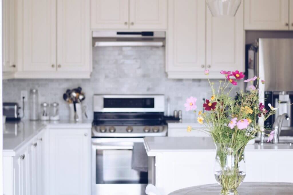 A freshly cleaned white kitchen with a bouquet of colorful flowers on the counter.