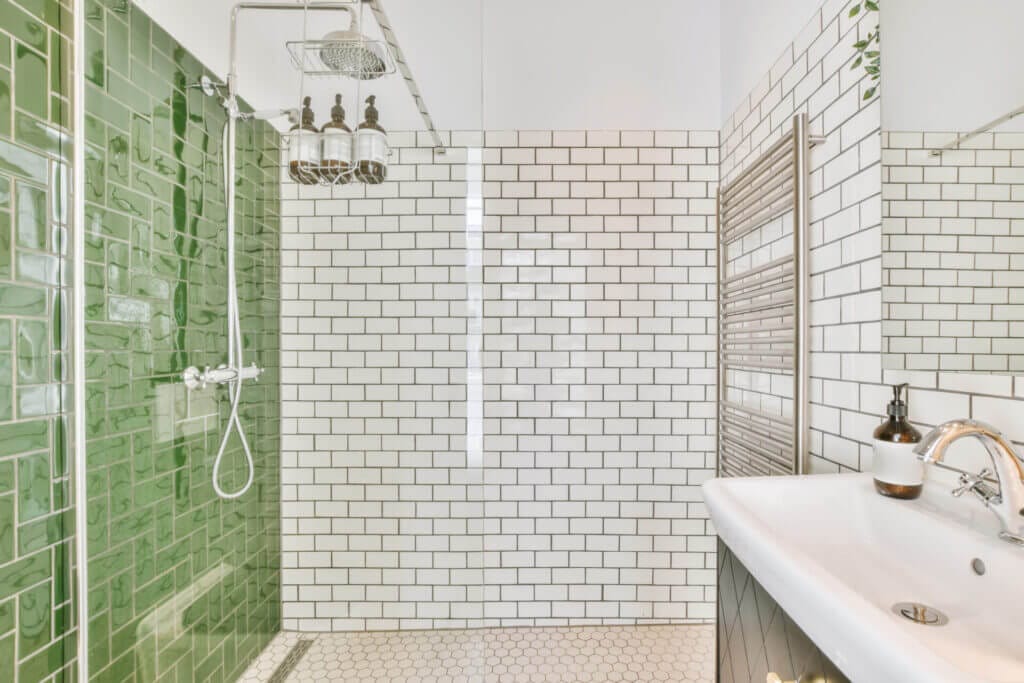 Spacious bathroom covered in white and green tiles.