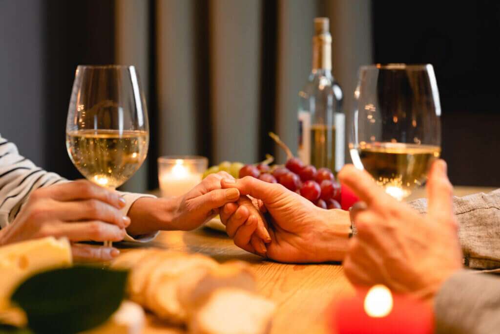 Couple holding hands at a romantic Valentine's dinner.
