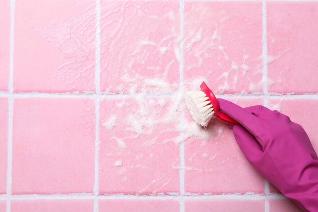 Pink tiles being polished and cleaned by a gloved hand.