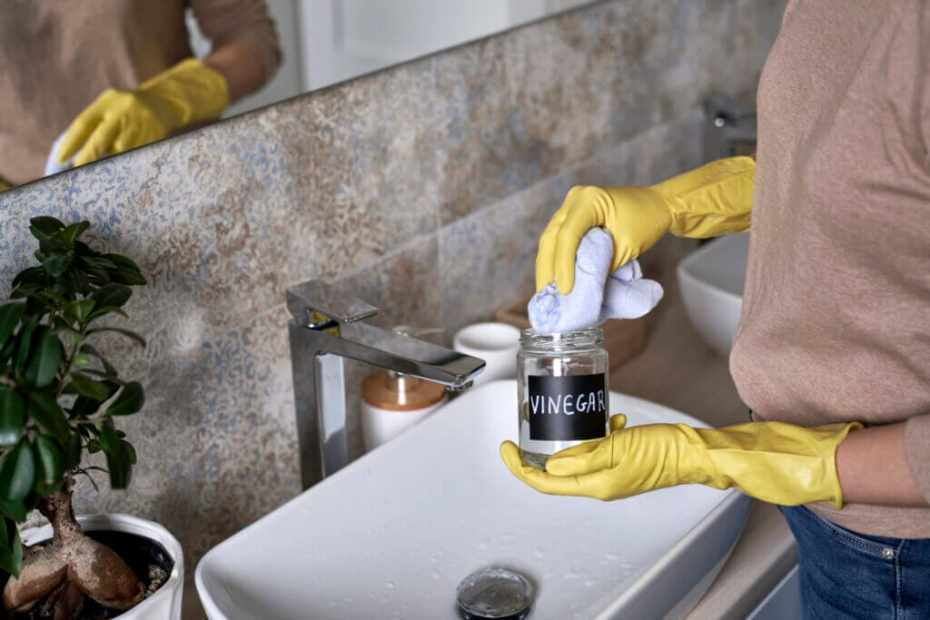 Woman cleaning mold from her bathroom using vinegar
