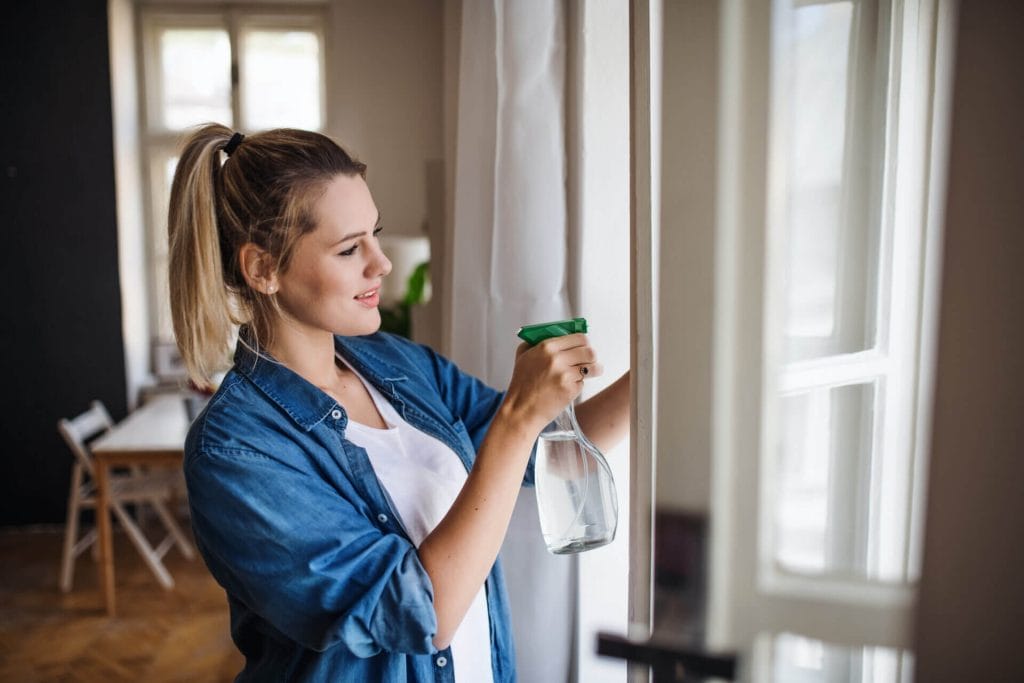 A woman cleaning her house following the guide of the 6/10 cleaning list