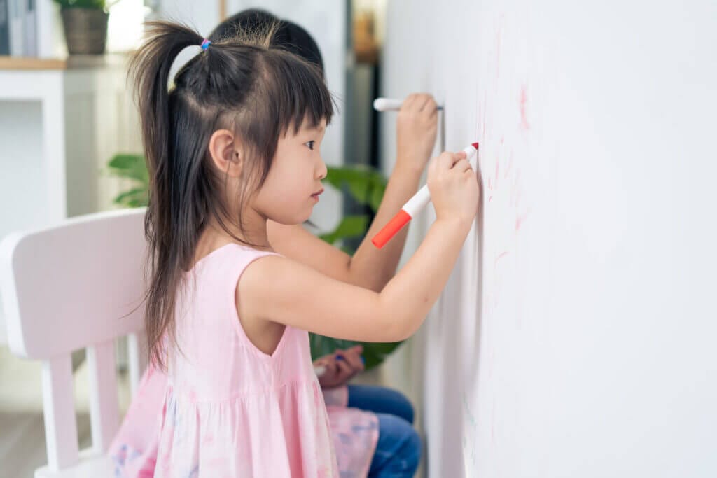 Two kids drawing on white wall