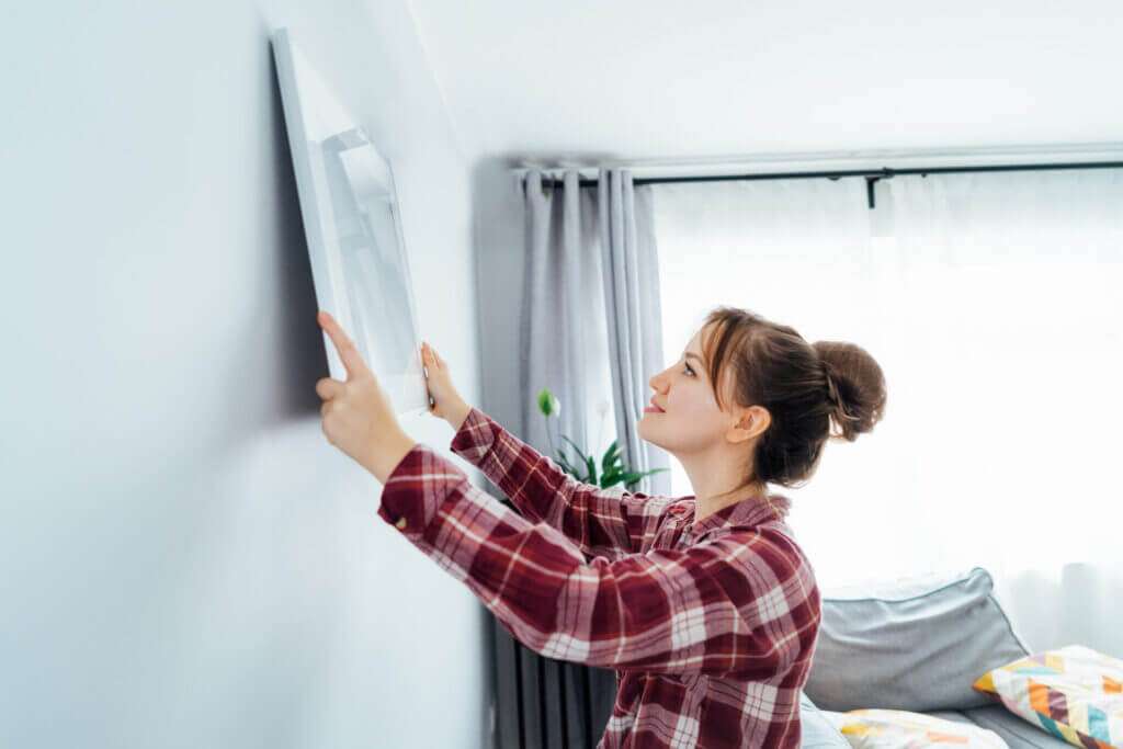 Young woman hanging a painting on her walls