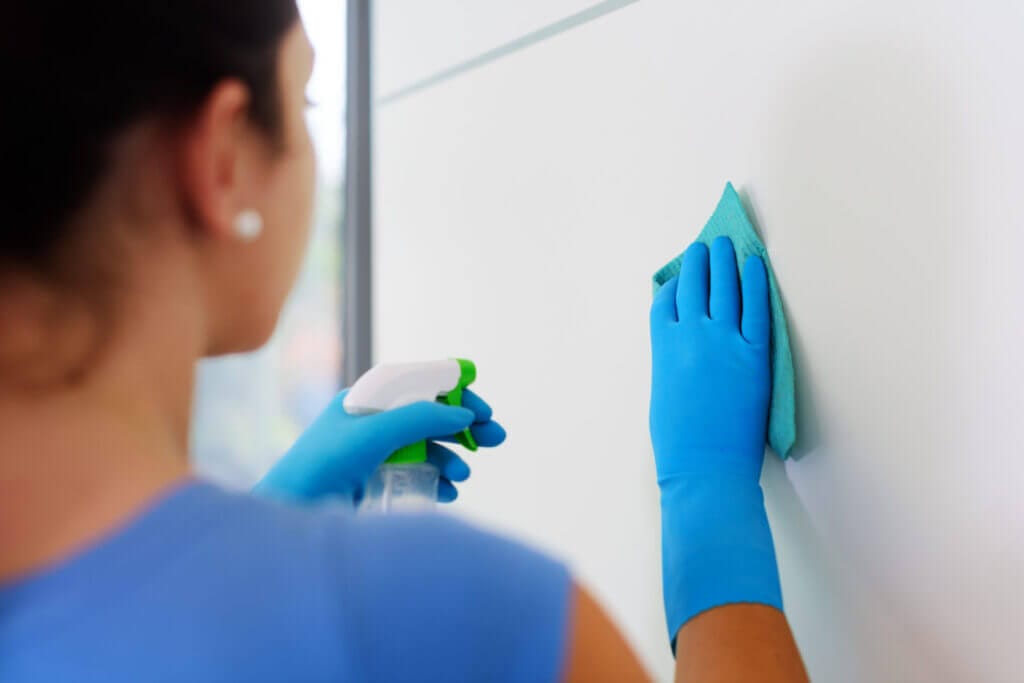 Girl with blue globes cleaning a white wall 