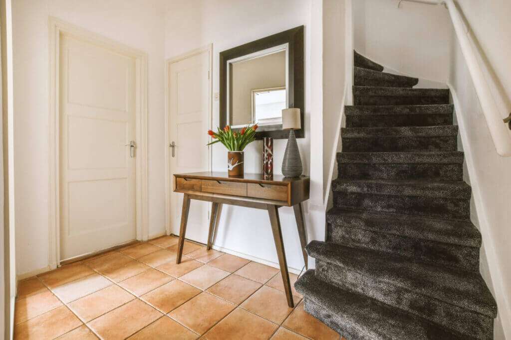 A spacious corridor with beautiful floors and a black carpeted stair