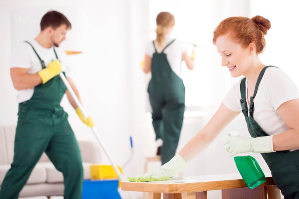 Three men and women from cleaning service deep cleaning a house
