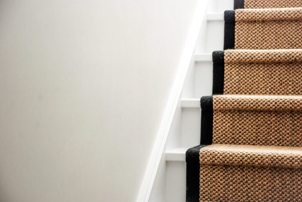 A white stairs in a house with a carpet on it