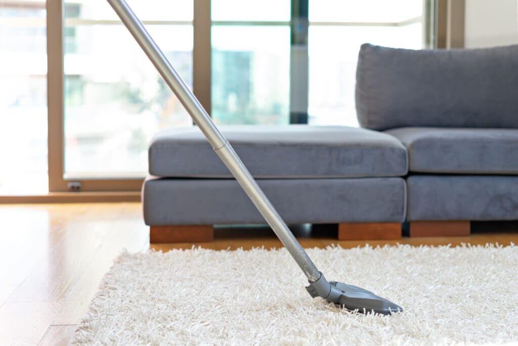 A person vacuuming their rug after learning how to keep carpet clean in high traffic areas.