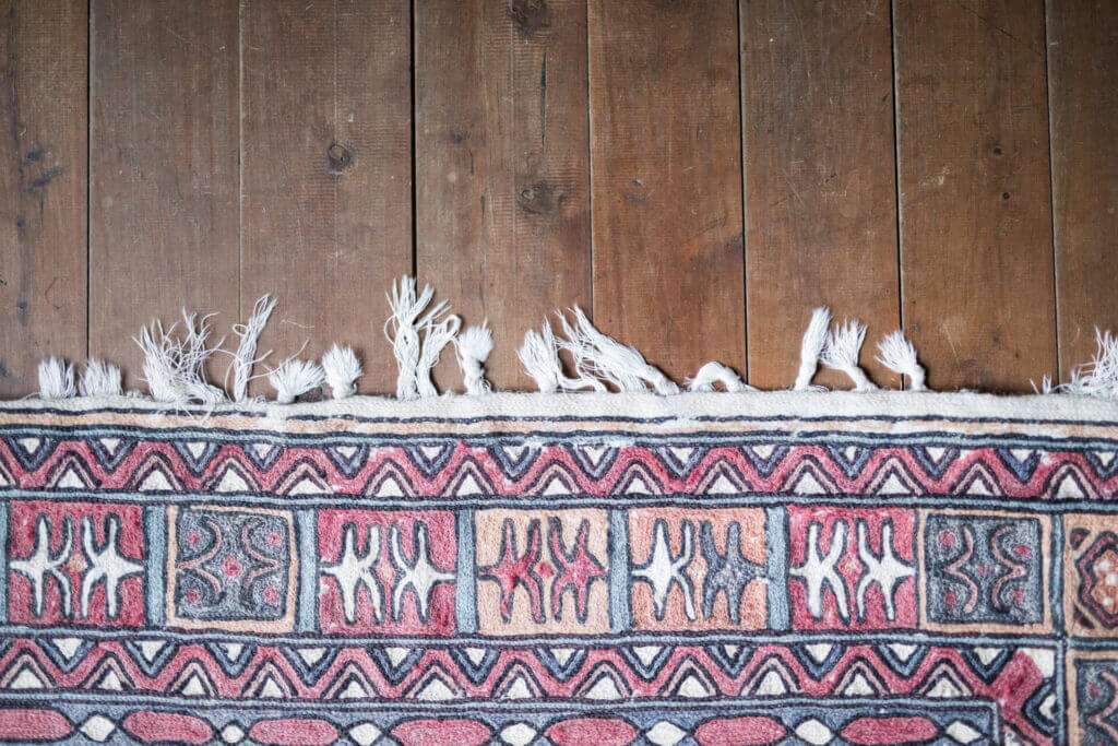 Clean Persian rug fringes over a wooden floor.