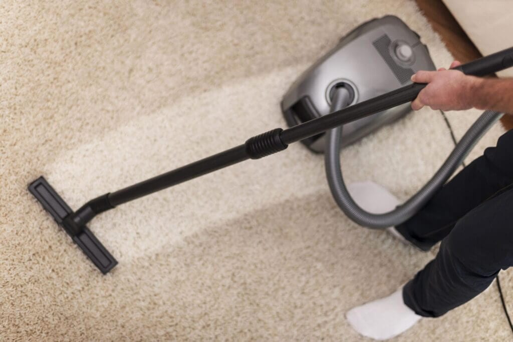 A person vacuuming their rug after learning how to keep carpets clean in high traffic areas