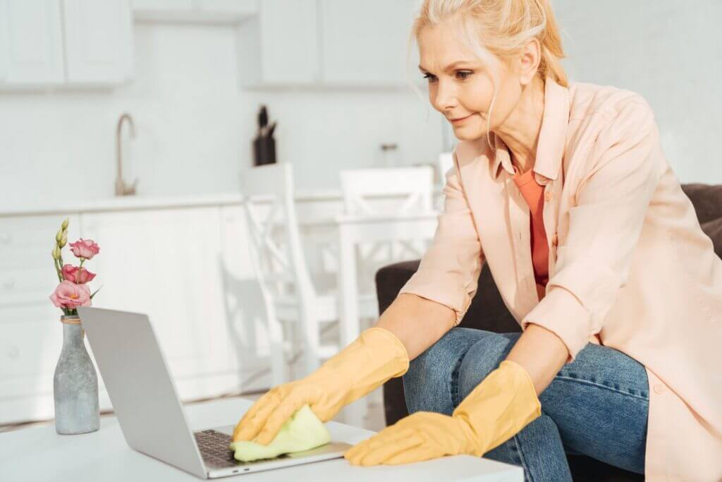 A senior woman showing how to clean electronics, in this case a laptop's keyboard