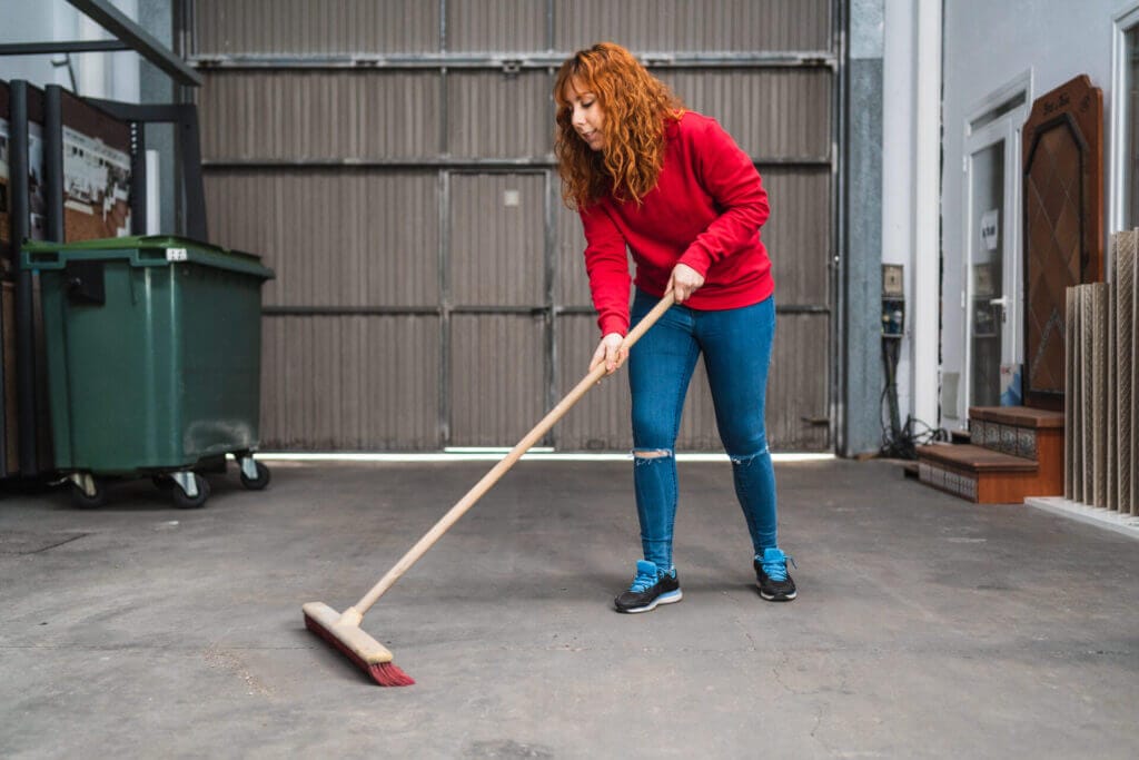 A person cleaning out the garage after learning how to clean garage walls